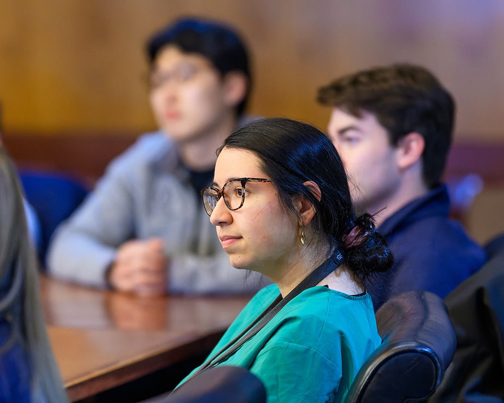 Medical students sit at a table and listen to Beauchamp speak